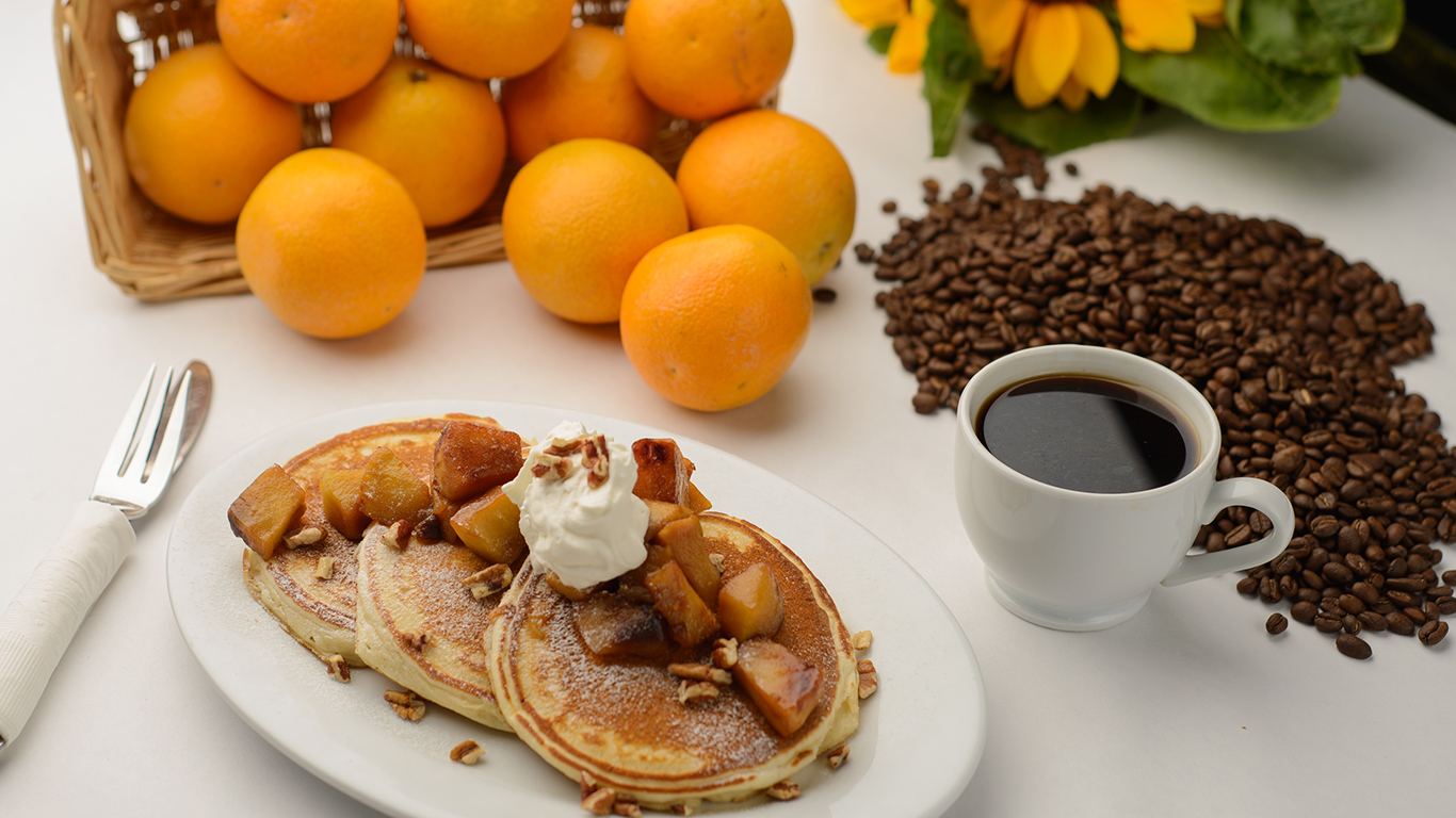 A breakfast spread with pancakes, coffee and oranges.